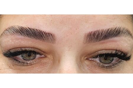 Green eyes with brow lamination and lash extensions.