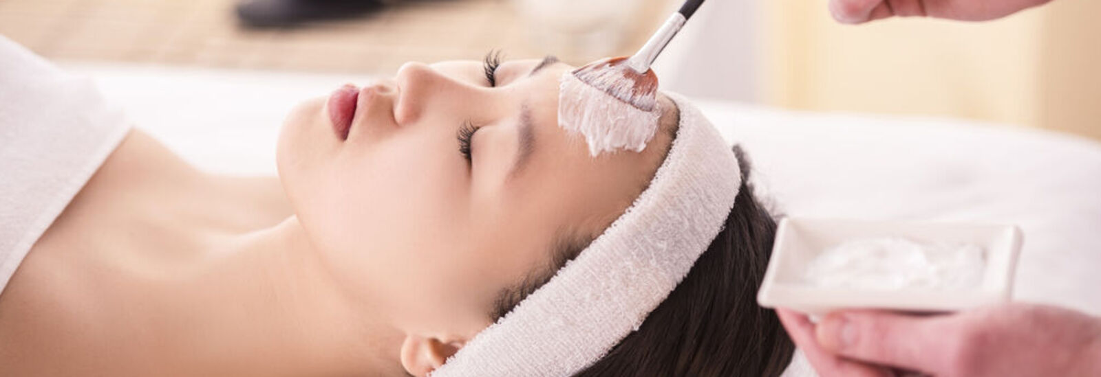 Woman with a white headband getting a facial 